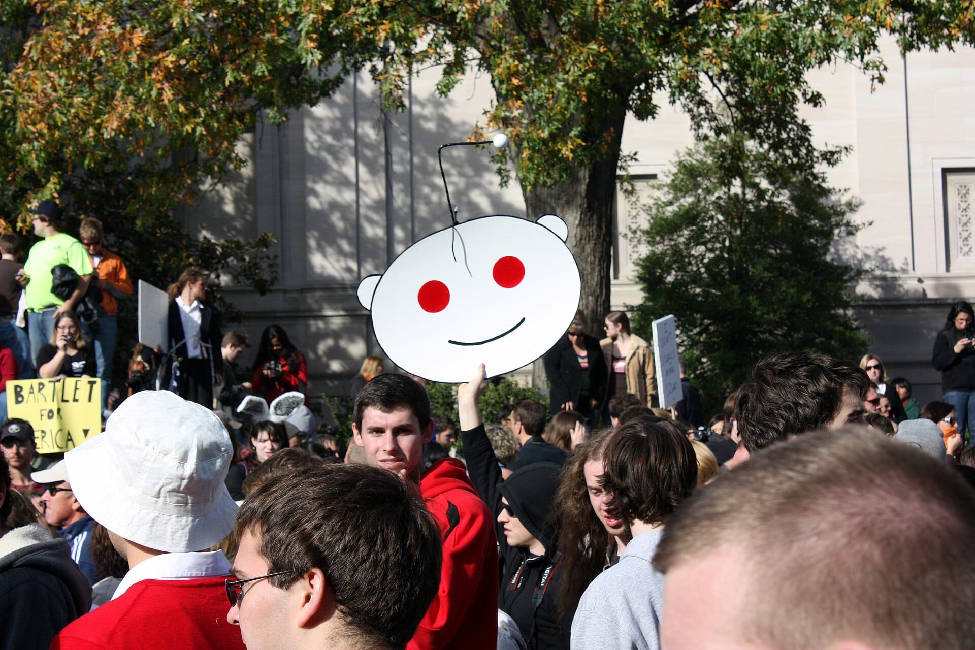 Manifestante con una sagoma del logo di Reddit durante una protesta