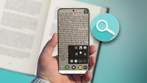 Mano che tiene uno smartphone con la lente di ingrandimento attiva sopra un libro aperto