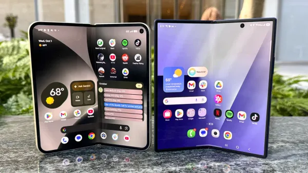 Due smartphone pieghevoli aperti affiancati su una superficie di pietra, con le schermate interne accese