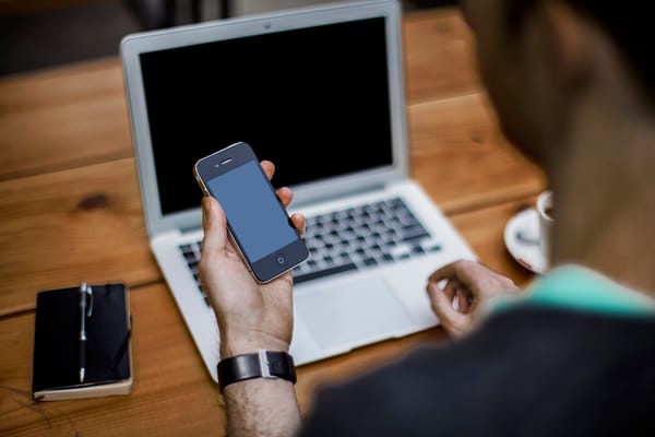 Persona che usa uno smartphone mentre lavora al computer