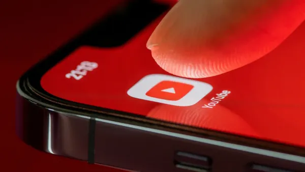 Primo piano di un dito che tocca l'icona YouTube sullo schermo di uno smartphone.