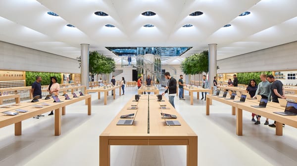 Interno dell’Apple Fifth Avenue: soffitto con lucernari, alberi, tavoli espositivi e clienti.