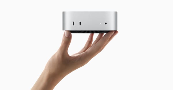 Mac mini M4 argentato mostrato in una mano, con le porte frontali visibili